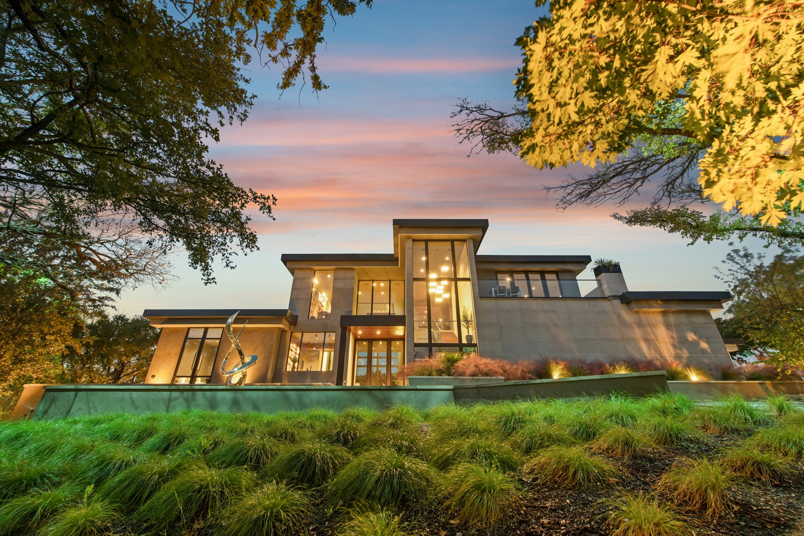 A modern two-storey house at sunset with its lights on